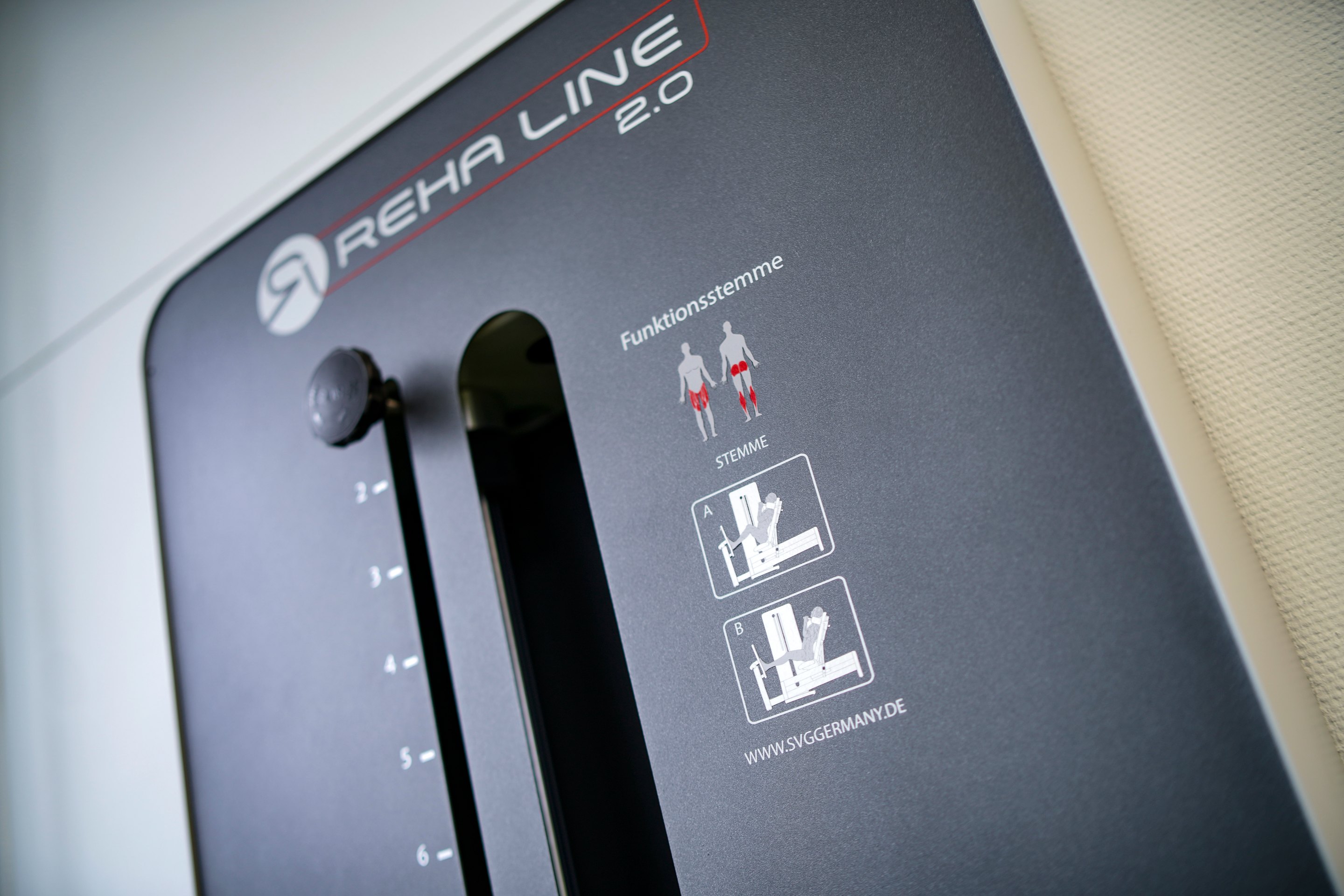 Nahaufnahme eines schwarzen Reha-Geräts mit der Aufschrift "REHA LINE 2.0" und Piktogrammen für Übungen.