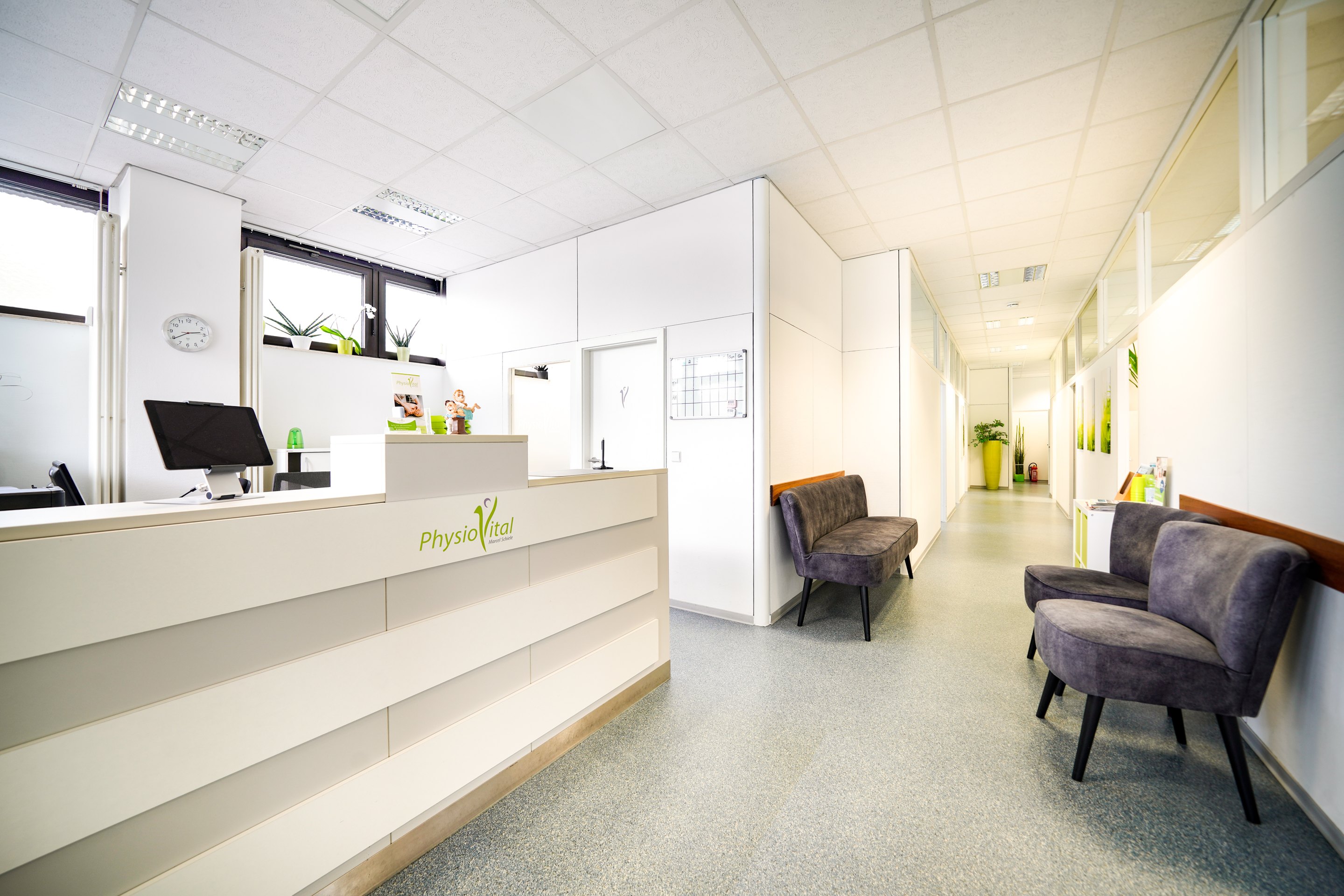 Heller Empfangsbereich einer Physiotherapiepraxis mit Rezeption, Wartebereich und Flur.